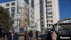 Жители стоят у дома пострадавшего от удара беспилотника, в Одессе, Украина, 19 февраля 2025 года.